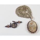 An Edwardian silver oval engraved locket with inlaid yellow metal flower, on silver chain plus a