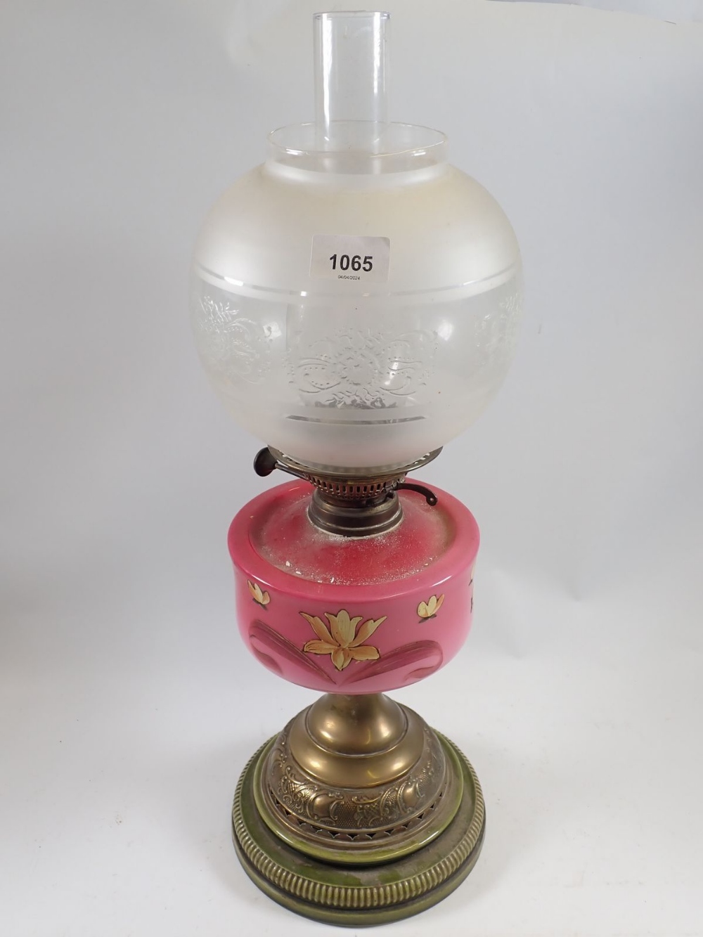 A Victorian oil lamp with pink floral painted glass reservoir, stoneware and brass base and etched