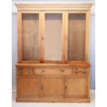 A large 19th century pine farmhouse cabinet with three glazed doors enclosing shelves over four