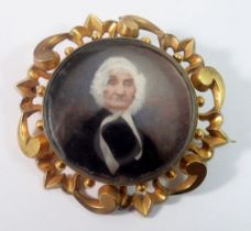 A Victorian gold mourning brooch painted miniature of an old lady within scrollwork surround,