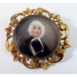 A Victorian gold mourning brooch painted miniature of an old lady within scrollwork surround,