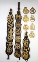 A group of various horse brasses mounted on leather and loose