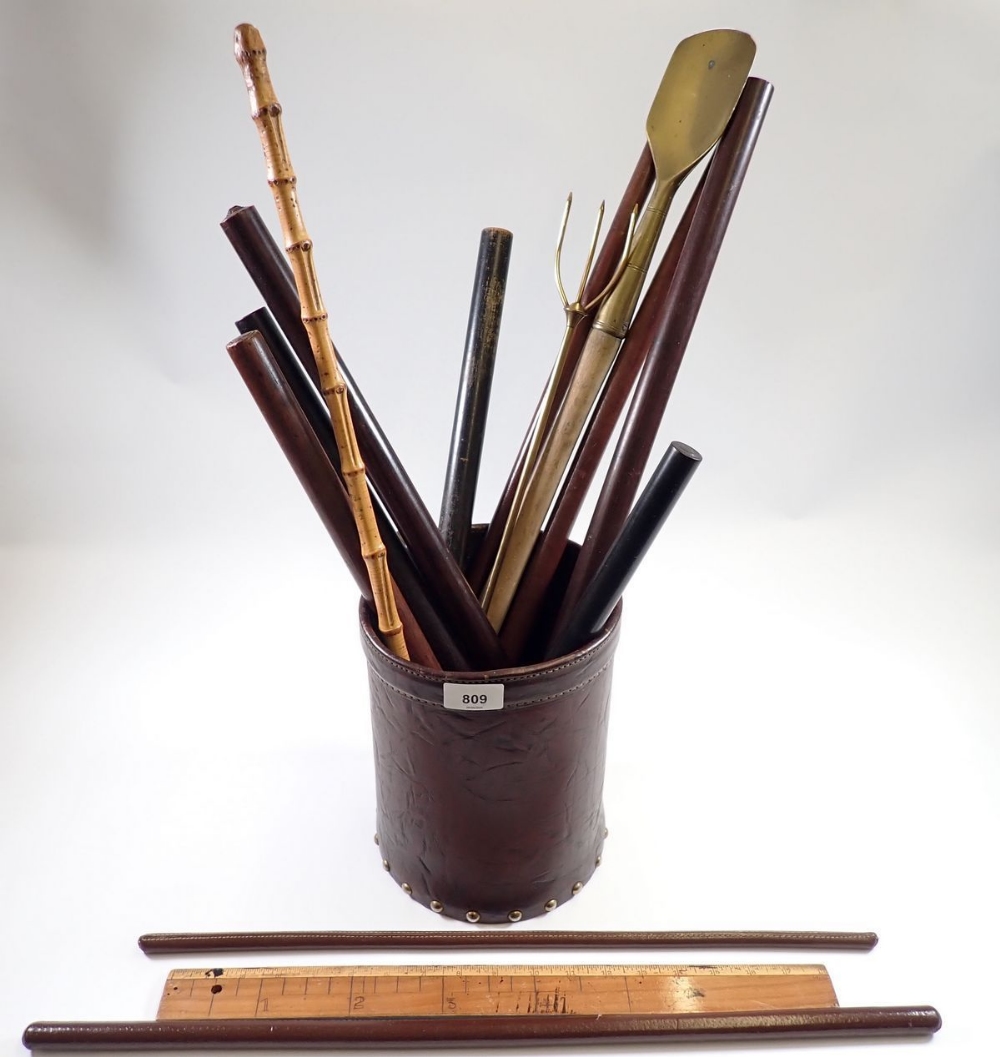 A collection of various swagger sticks, circular rulers and measuring sticks etc. in leather bin (