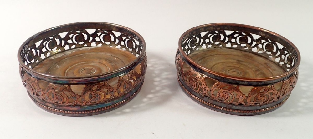 A pair of Georgian silver plate on copper bottle coasters on turned wood bases