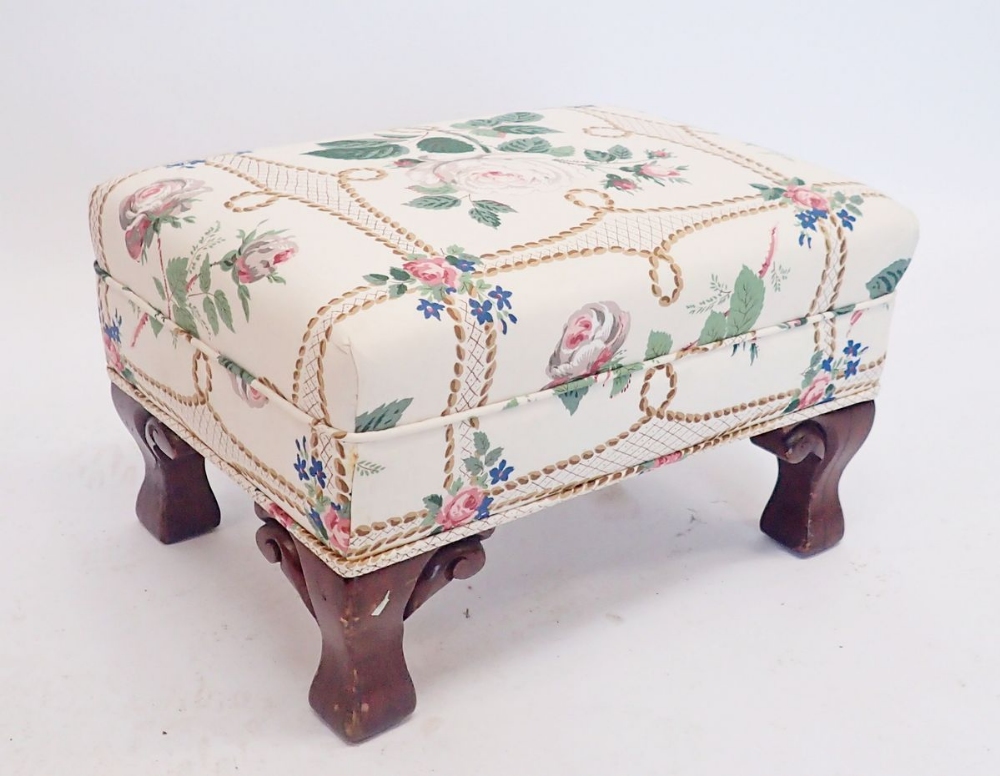 A Victorian floral upholstered footstool on carved scroll feet