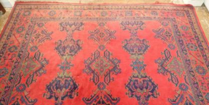A large Turkish carpet with blue and green motifs on a red ground, 340 x 368cm
