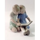 A German porcelain group of two children seated reading by Carl Sheidig, 10cm tall