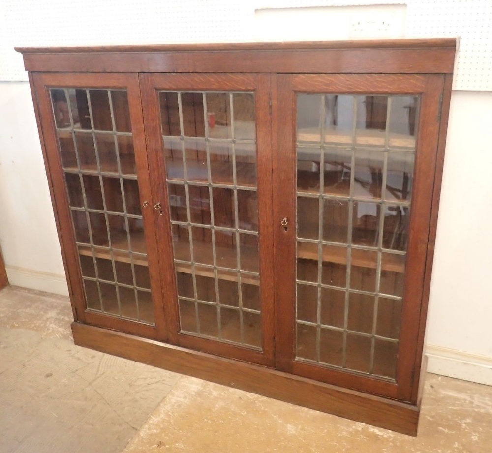 An early 20th century oak lead glazed dwarf bookcase with three doors enclosing shelves, 156cm