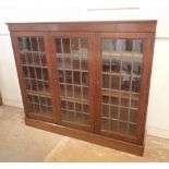 An early 20th century oak lead glazed dwarf bookcase with three doors enclosing shelves, 156cm