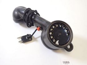 An early 20th century telephone hand receiver/handset with dial to reverse of mouthpiece