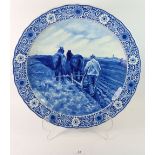 A Delft large circular dish painted ploughing scene, signed Mauve, 41cm diameter