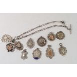 A silver fancy link fob chain and eleven silver fobs and medals