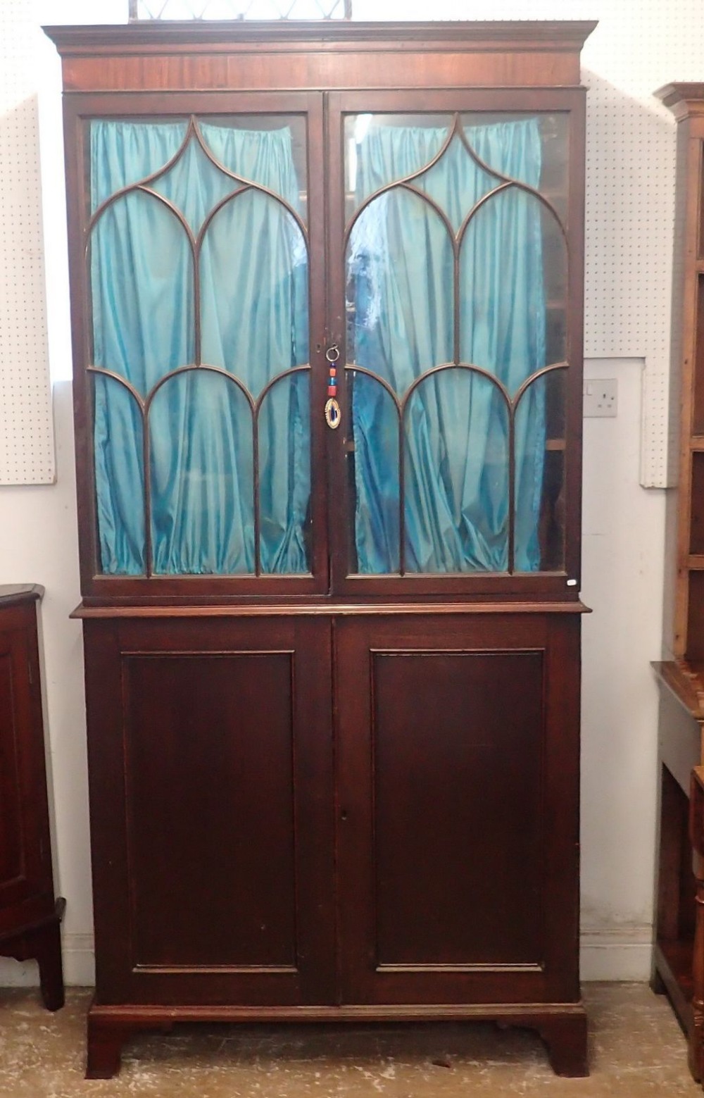 A Regency mahogany bookcase with two Gothic arch glazed doors over panelled cupboard, all on bracket