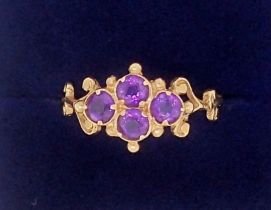 An antique style 9 carat gold ring set four amethysts in scrollwork and beaded surround, 1.6g,