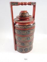 A Burmese tiffin food carrier in red with animal decoration, 36.5cm tall