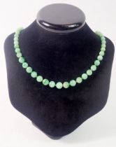 A jade bead necklace with 9 carat gold clasp set chip diamonds and emeralds