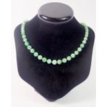A jade bead necklace with 9 carat gold clasp set chip diamonds and emeralds
