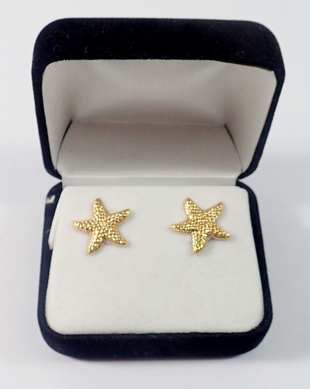 A pair of gold star fish earrings, boxed, 1g