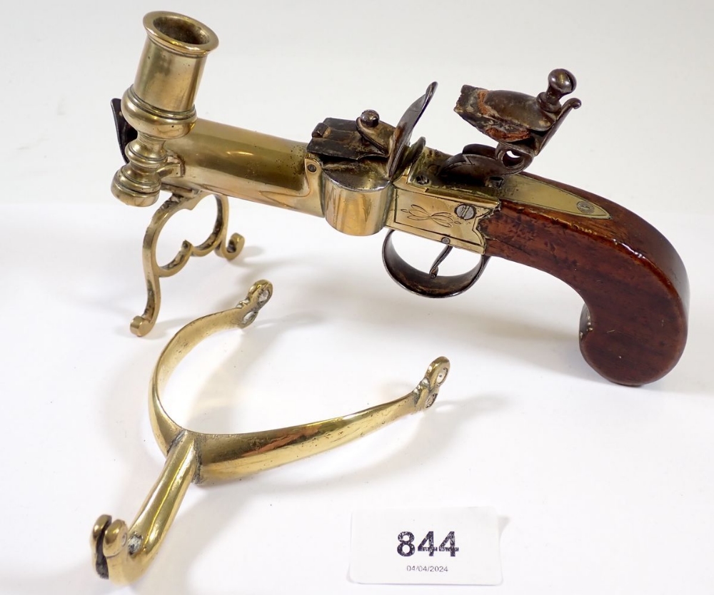 An antique percussion action pistol table lighter with taper stick, 17cm long and a brass stirrup