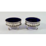 A pair of Edwardian oval silver salts with pierced decoration and blue glass liners, London 1905/