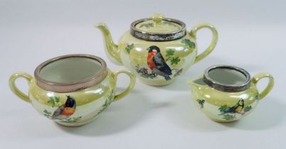 A yellow lustre teapot, milk jug and sugar bowl printed birds, with silver rims, Birmingham 1926