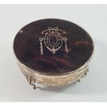 A silver and tortoiseshell circular dressing table box, the lid with ribbon and husk inlay, 11cm