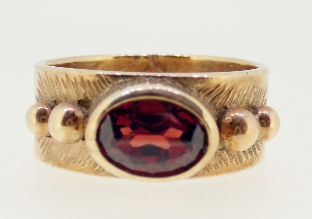 A 9 carat gold ring rub over set oval garnet on wide band and beaded shoulders, size L, 5.3g - Image 2 of 4