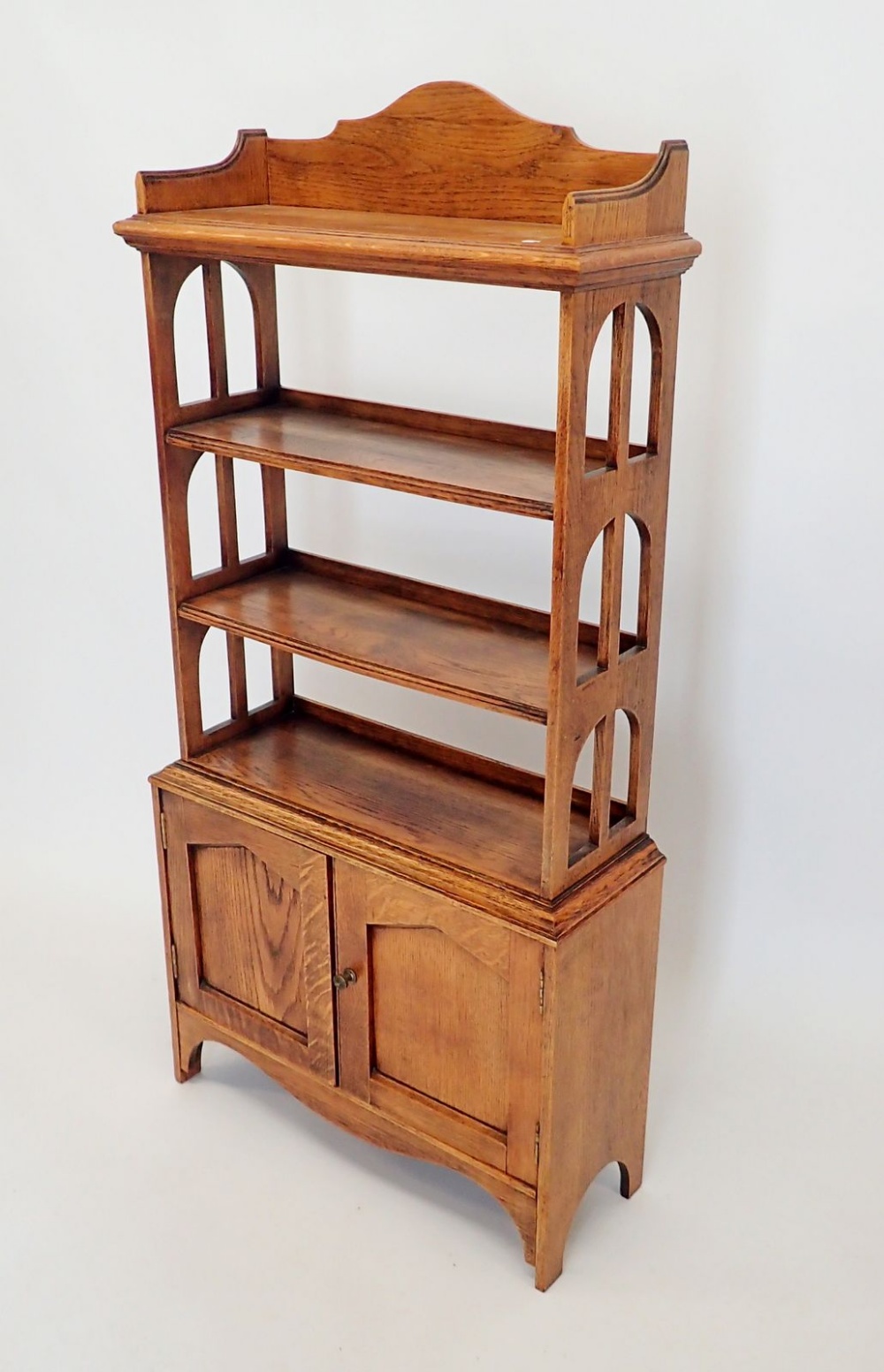 An early 20th century open oak bookcase with three shelves over cupboard, 60x128cm