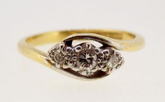 An 18 carat gold and platinum three stone diamond crossover ring, size K, 2.8g