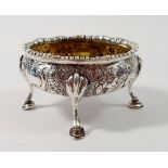 A George III silver oval salt on four hoof feet with embossed floral and scroll decoration, London