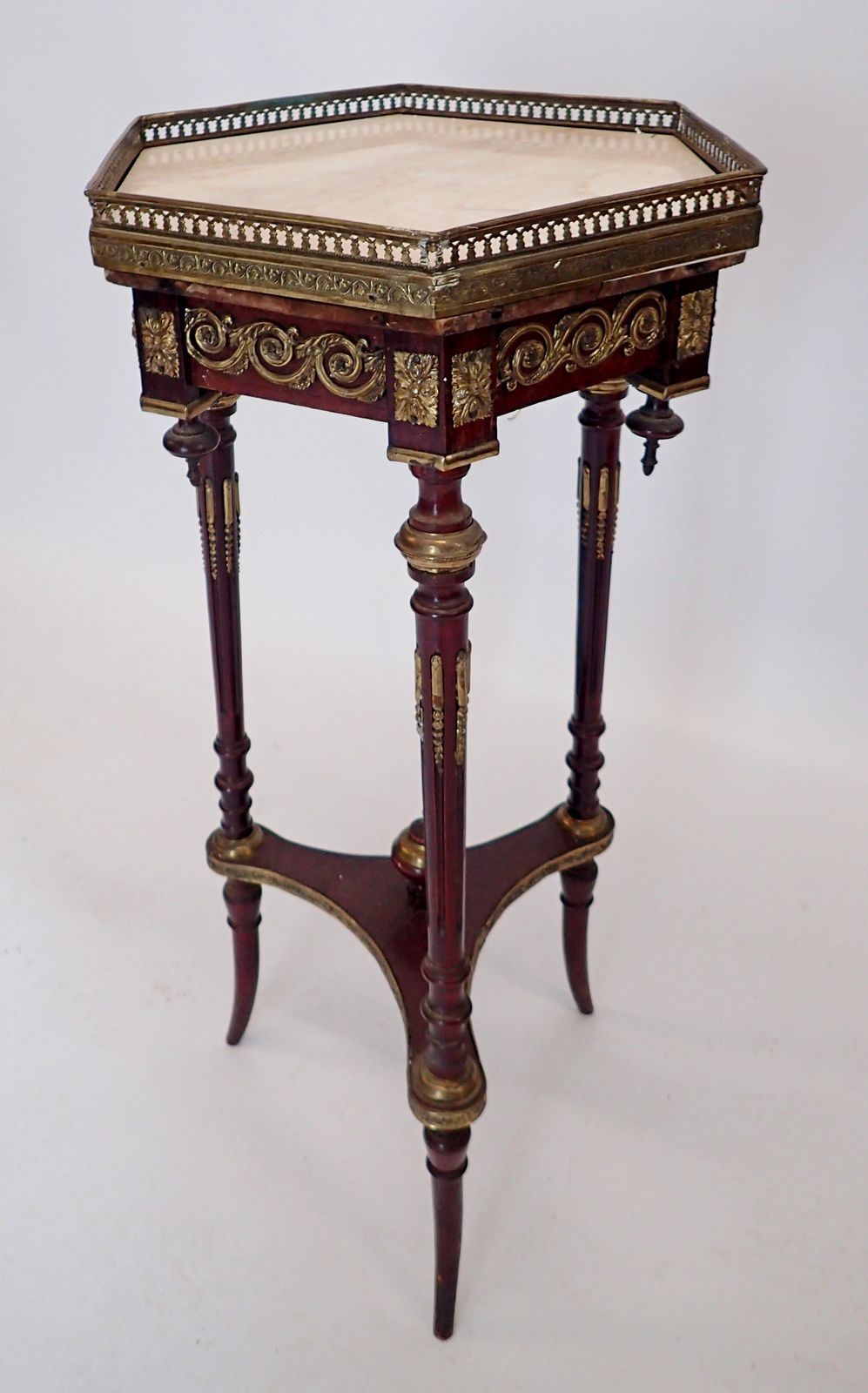 A French hexagonal marble topped mahogany occasional table with three slender supports united by