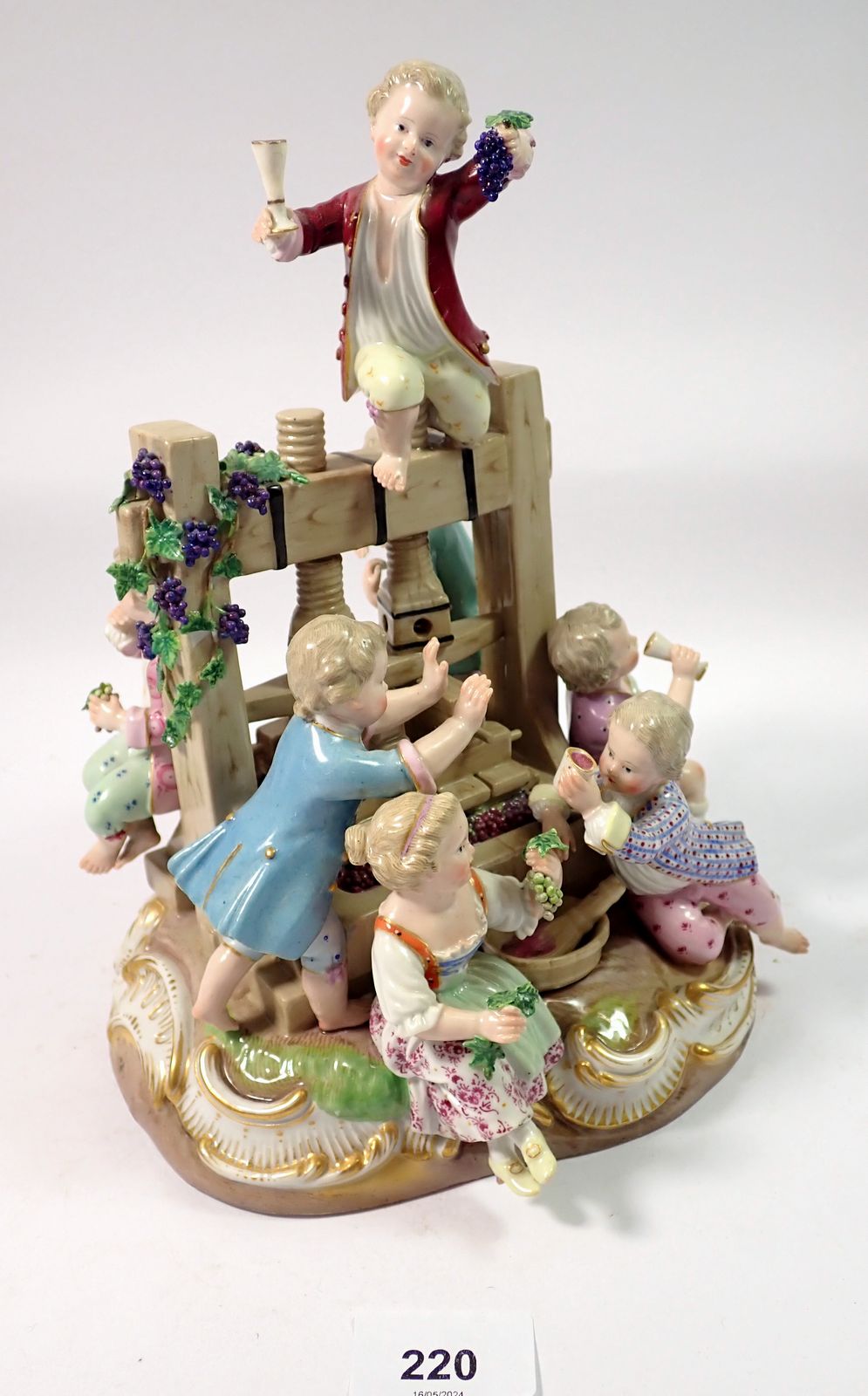 A 19th century Meissen group of children playing around a wine press, crossed swords mark to base,