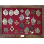 A framed display of twenty four military cap badges including examples of Argyle and Sutherland