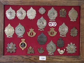 A framed display of twenty four military cap badges including examples of Argyle and Sutherland