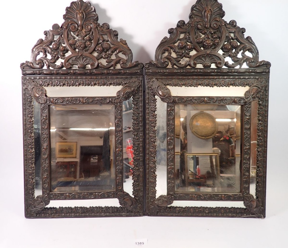 A pair of Flemish style patinated brass cushion framed mirrors, 59 x 33cm