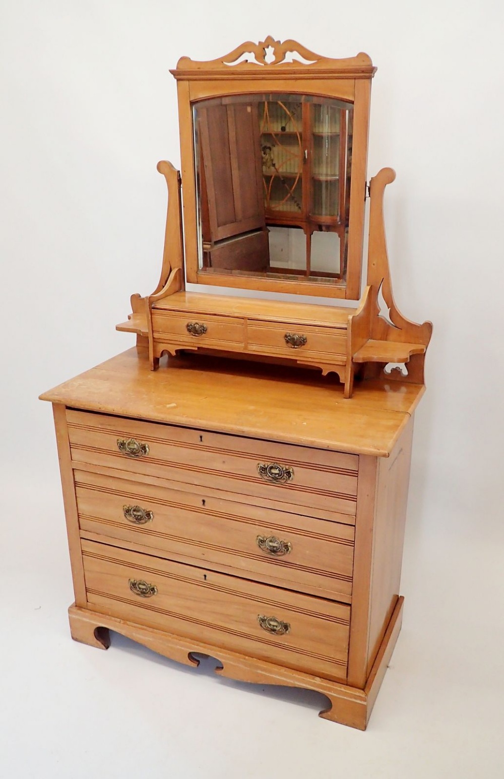 An Edwardian satinwalnut dressing table with swing mirror and trinket drawers over two short and two