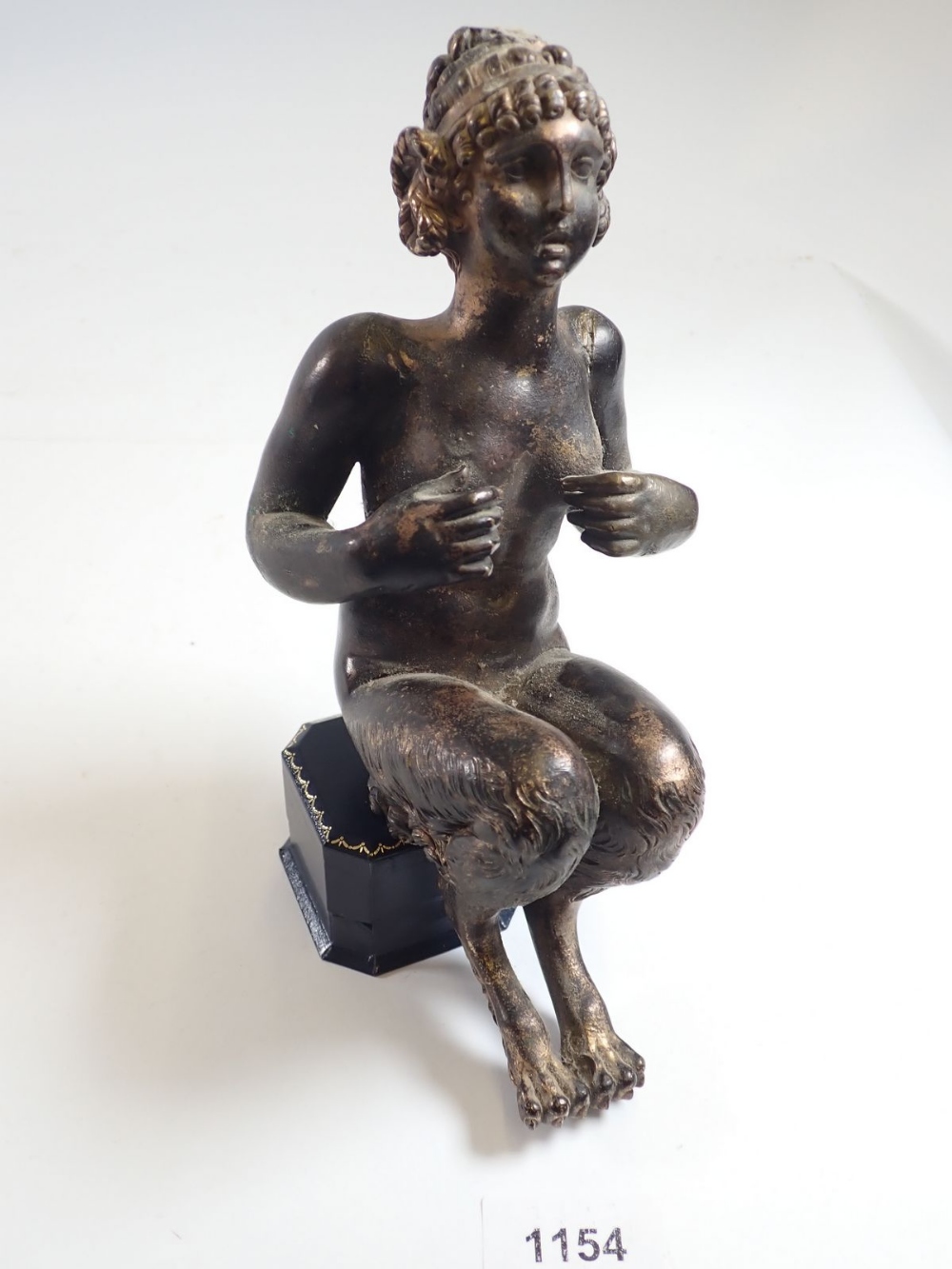 An antique bronze figure of a female faun seated (lacking base) 22cm tall