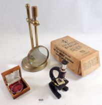 A brass magnifying glass on stand and a students microscope etc.