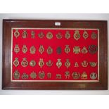 A framed display of forty numbered regimental military cap badges