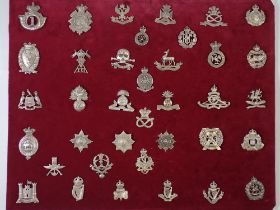 A framed and glazed display of thirty six white metal military cap badges, all marked 'silver'