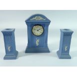 A Wedgwood Jasperware mantel clock, 22cm tall with a pair of similar candlesticks