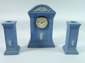 A Wedgwood Jasperware mantel clock, 22cm tall with a pair of similar candlesticks