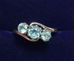 An 18 carat gold and platinum crossover set three blue topaz ring, size M, 3g