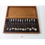 A set of twelve Eastern white metal spoons in carved wood fitted case