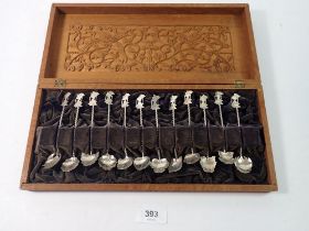 A set of twelve Eastern white metal spoons in carved wood fitted case