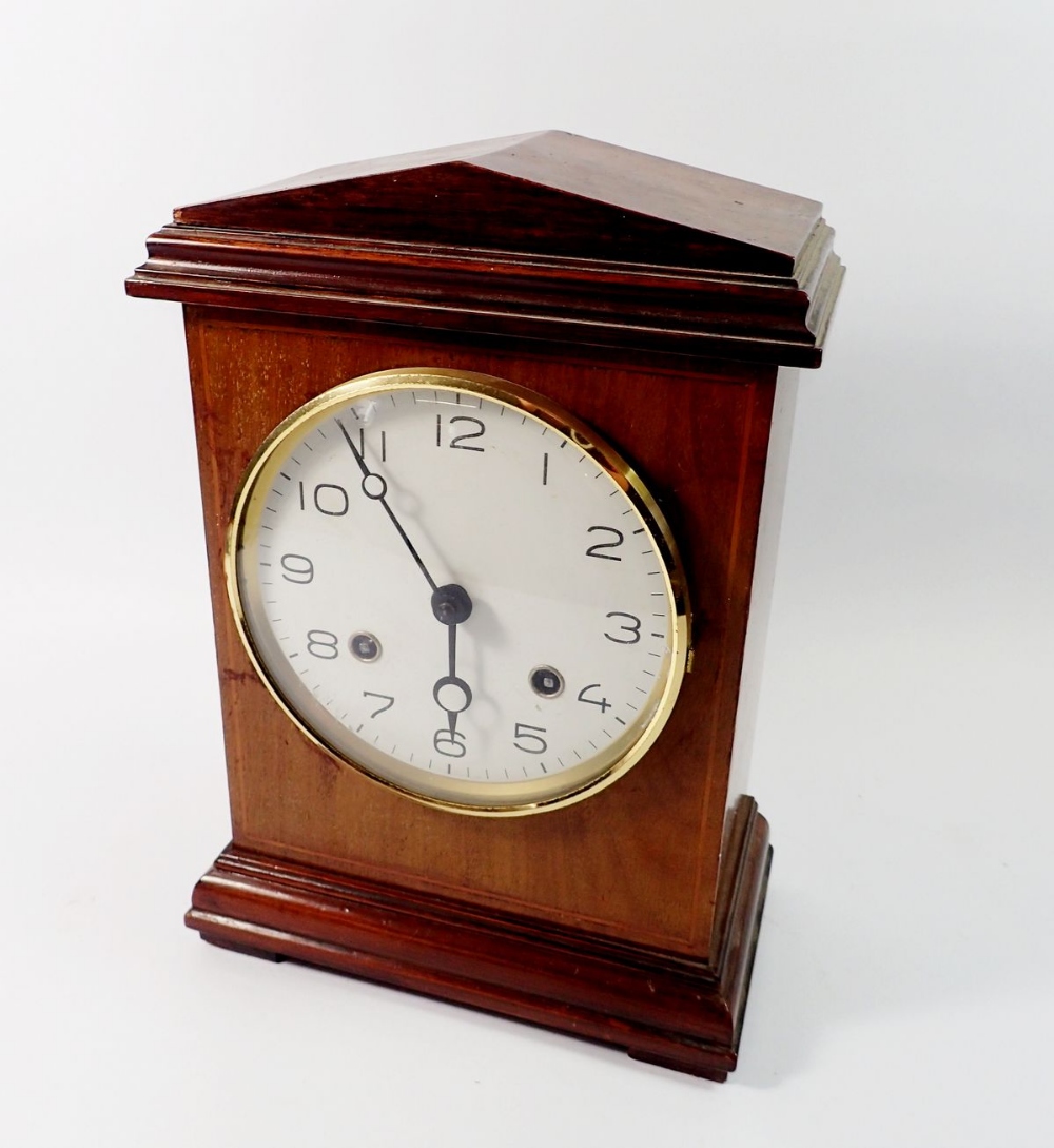A 19th century mahogany mantel clock with arch top and enamel dial with pendulum and key, 31cm tall