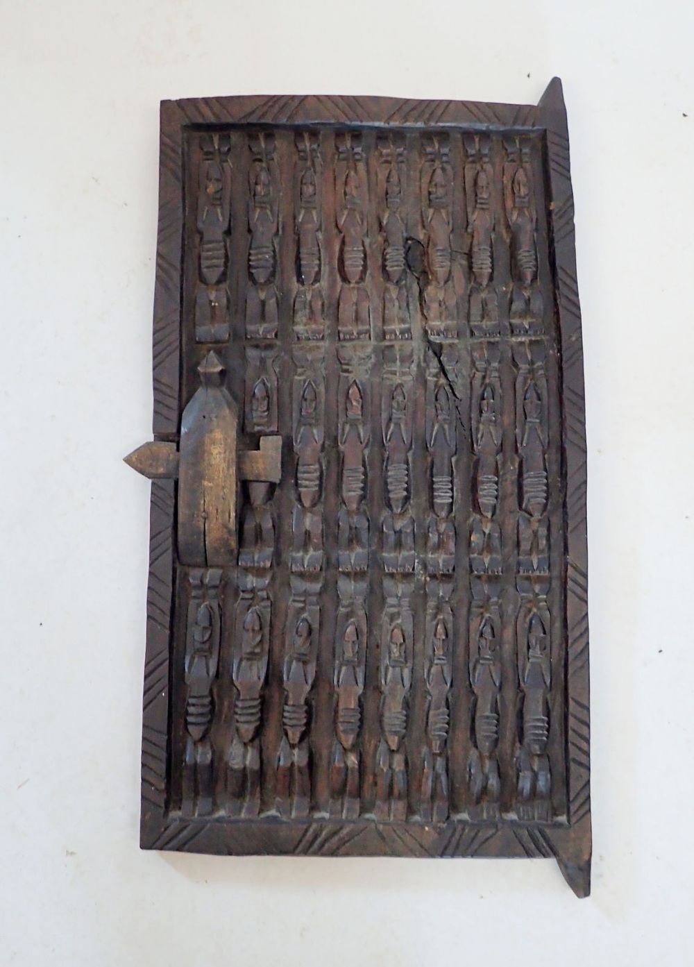A carved Dogon tribal door, thought to be from a granary grain store in Mali, decorated three rows