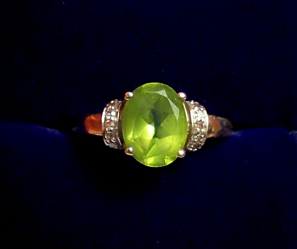 A 9 carat gold ring set peridot flanked by chip diamonds, size J, 2.5g