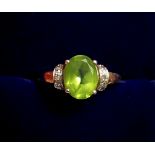 A 9 carat gold ring set peridot flanked by chip diamonds, size J, 2.5g