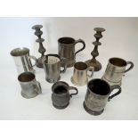 A collection of pewter tankards and a pair of candlesticks